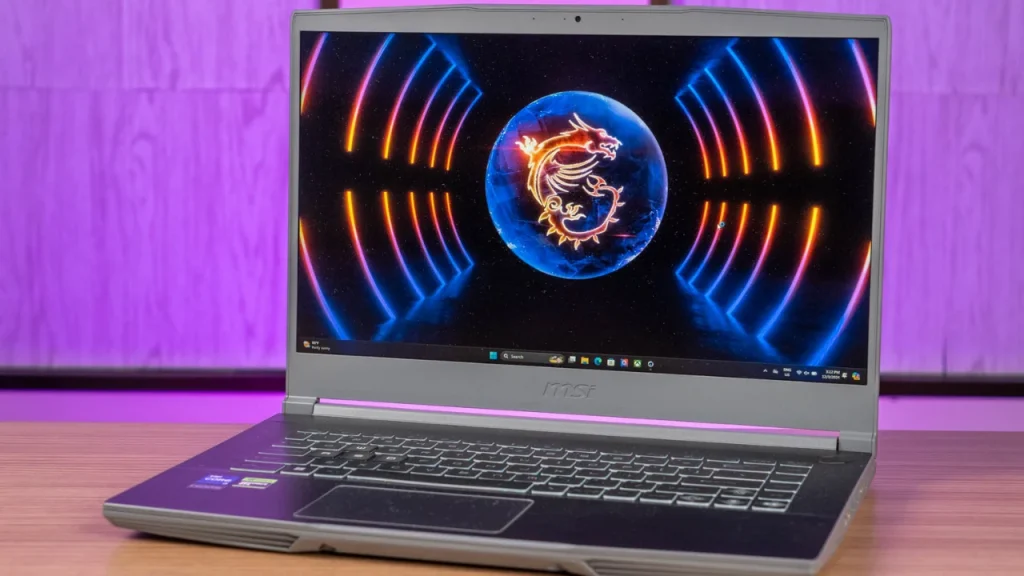 Top 10 Laptop Brands in 2026. An open MSI gaming laptop sitting on a wooden desk, featuring a vibrant, animated dragon logo on the screen and a backlit keyboard.